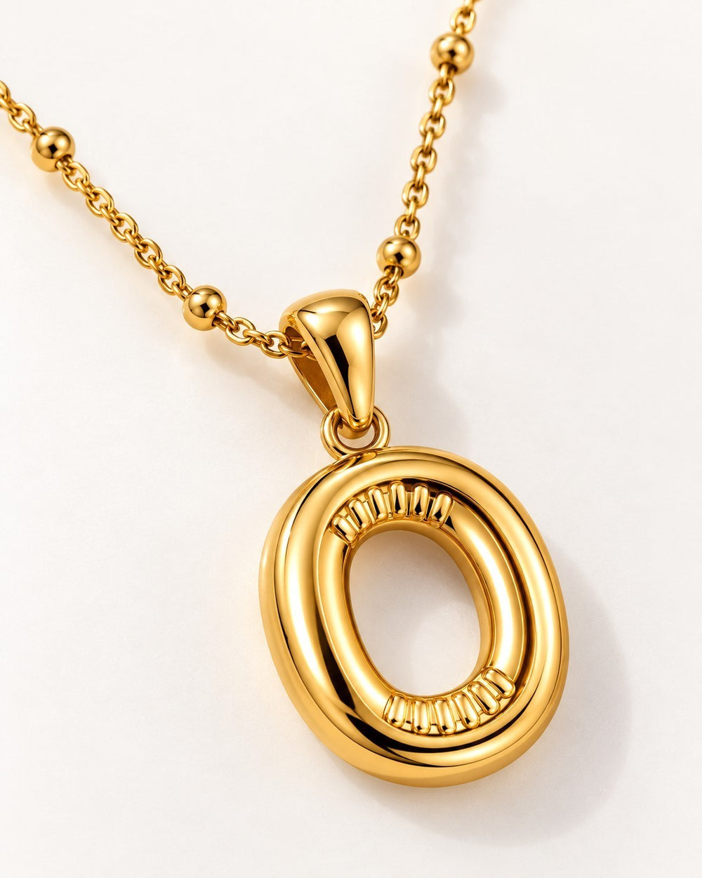 Elli Jewellery gold plated chunky initial O pendant necklace on a delicate beaded chain against a white background.
