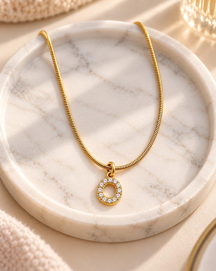 Elli Jewellery gold plated waterproof initial O pendant necklace with crystal accents on a marble tray