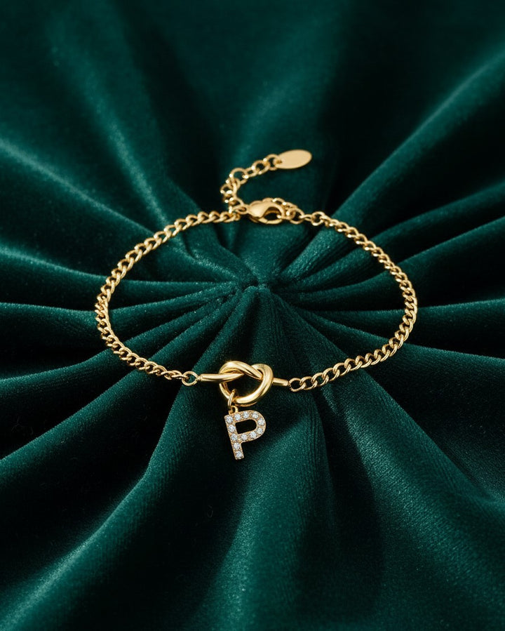 Elli Jewellery gold plated tennis bracelet featuring a diamante initial P charm on a delicate chain against green velvet