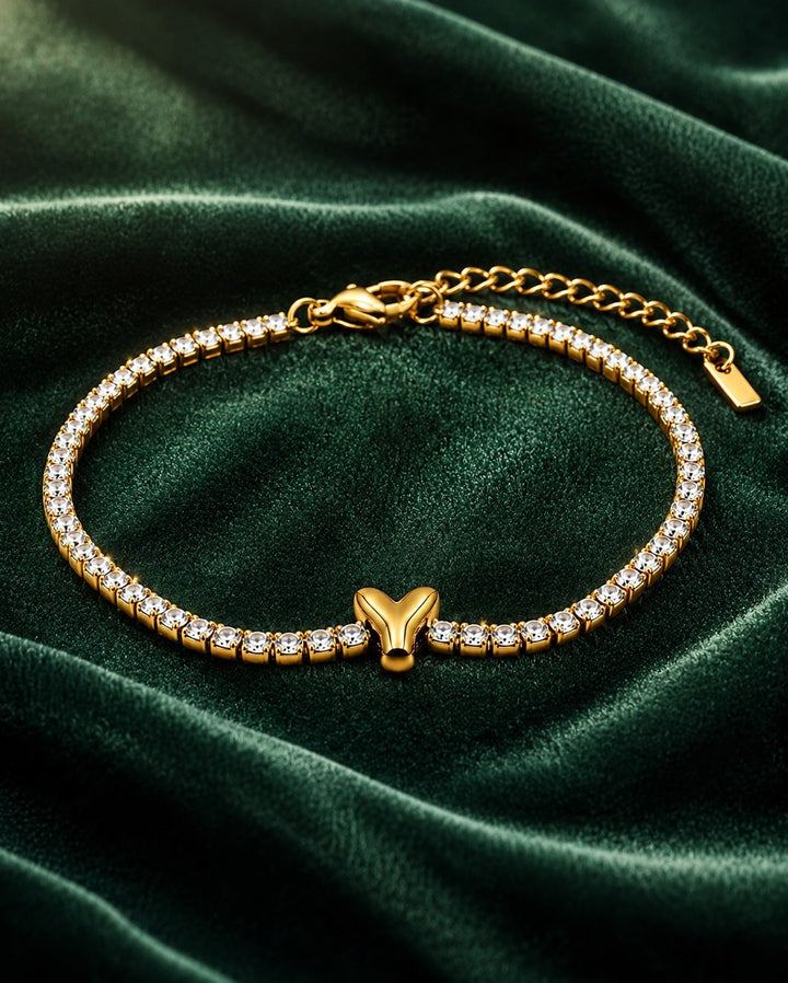 Elli Jewellery gold plated waterproof tennis bracelet featuring a polished initial Y charm on a green velvet background
