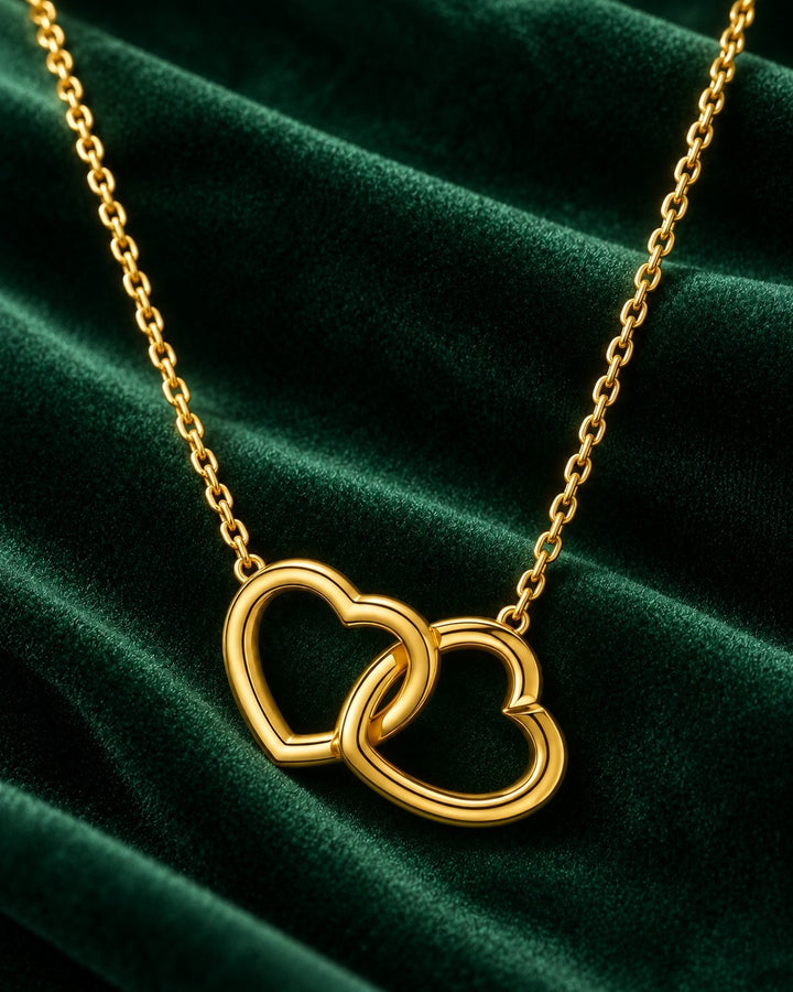Elli Jewellery gold plated waterproof necklace featuring two intertwined hearts on a delicate chain against green velvet