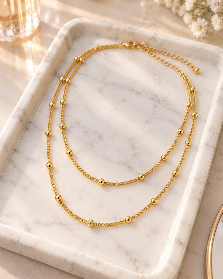 Elli Jewellery gold plated triple layered beaded chain necklace on a marble tray