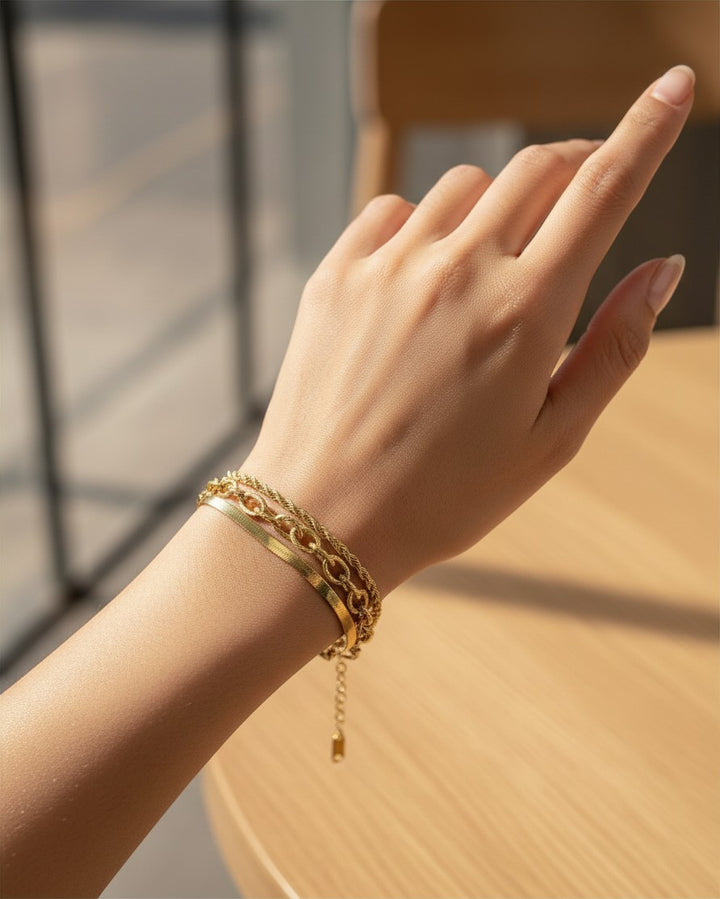 Elli Jewellery gold-plated multi-layered charm bracelet worn on a woman's wrist, featuring delicate chain textures.