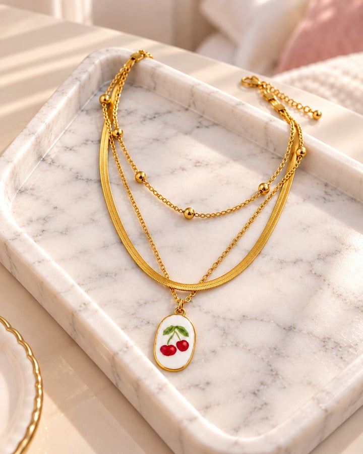 Elli Jewellery gold-plated layered snake chain necklace featuring a white oval pendant with red cherry charms