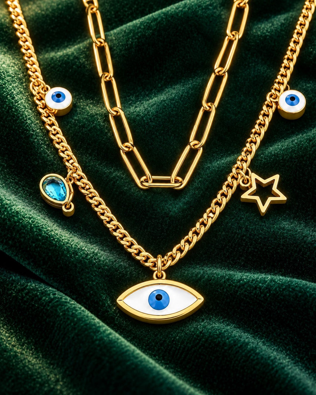 Elli Jewellery gold plated layered necklace with paperclip chain, evil eye charms, and star pendant on green velvet.