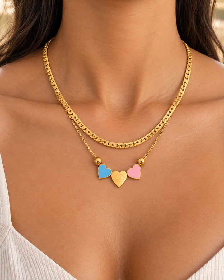 Elli Jewellery gold plated layered chain necklace featuring blue, gold, and pink heart charms on a woman's neck