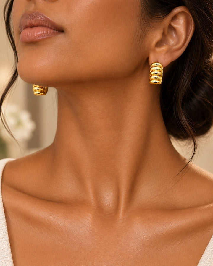 Elli Jewellery gold plated multi-layer stud earrings worn by a model, featuring a textured, stacked design.
