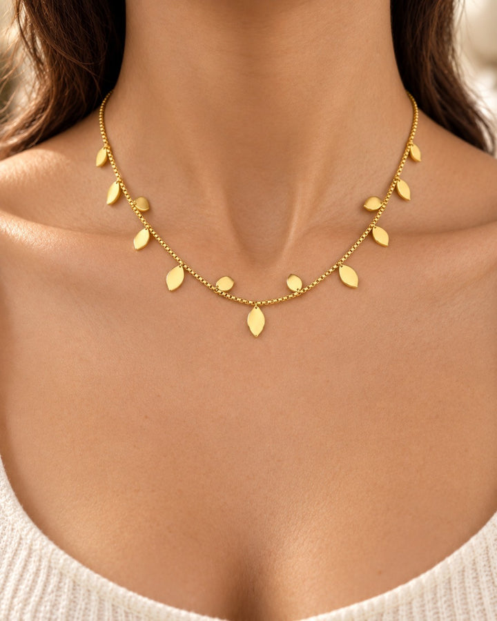Elli Jewellery gold plated botanical leaf statement necklace worn on a woman's neck, featuring delicate leaf charms.