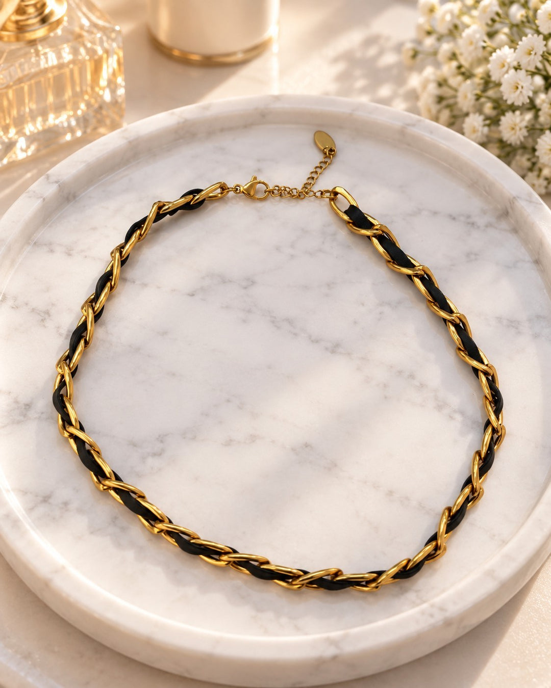 Elli Jewellery gold-plated curb chain necklace interwoven with black leather, displayed on a marble tray.