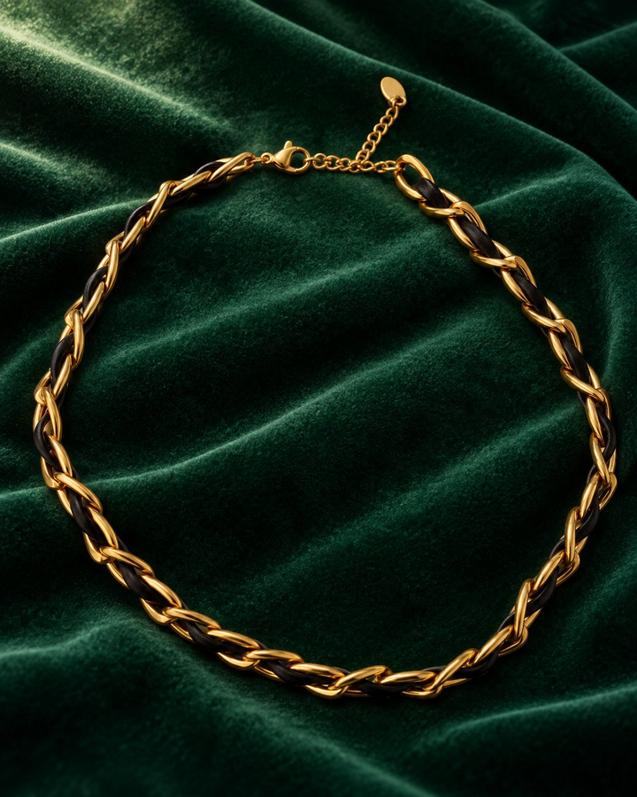 Elli Jewellery gold-plated curb chain necklace interwoven with black leather on a dark green velvet background