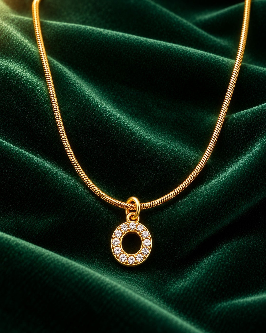 Elli Jewellery gold plated letter O pendant necklace with sparkling crystals on a green velvet background
