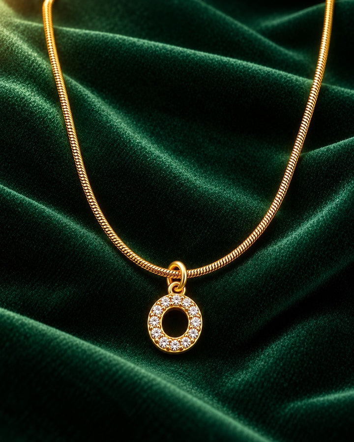 Elli Jewellery gold plated letter O pendant necklace with sparkling crystals on a green velvet background