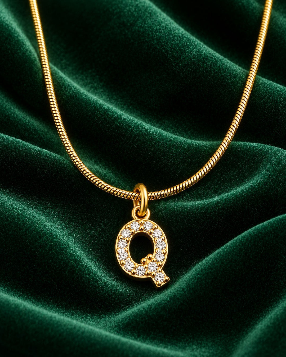 Elli Jewellery gold plated letter Q pendant necklace with sparkling crystals on a green velvet background