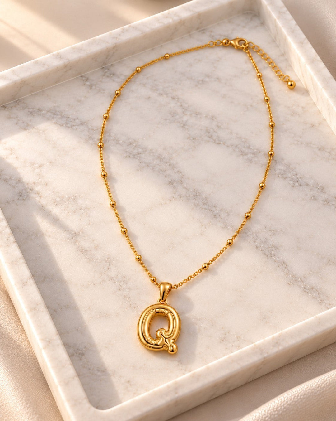 Elli Jewellery gold-plated chunky letter Q initial pendant necklace on a marble tray