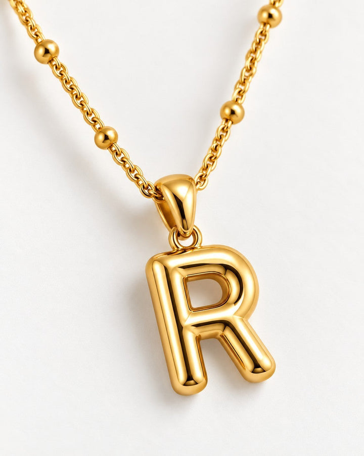 Elli Jewellery chunky gold plated letter R initial pendant necklace on a delicate beaded chain against white background