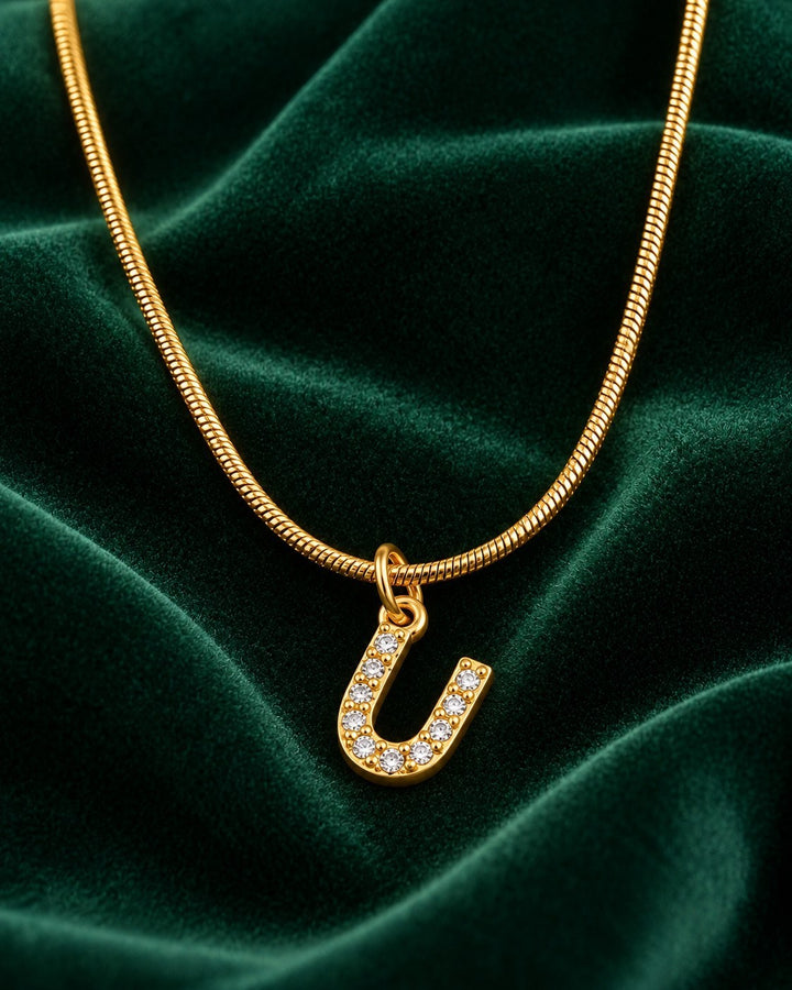 Elli Jewellery gold plated letter U initial pendant necklace with sparkling crystals on a green velvet background
