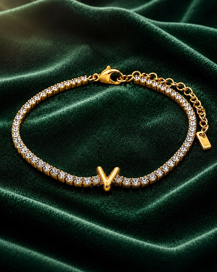 Elli Jewellery gold plated tennis bracelet featuring a letter V initial charm with sparkling crystals on green velvet