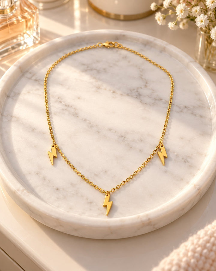 Elli Jewellery gold plated waterproof necklace featuring three delicate lightning bolt charms on a marble tray.