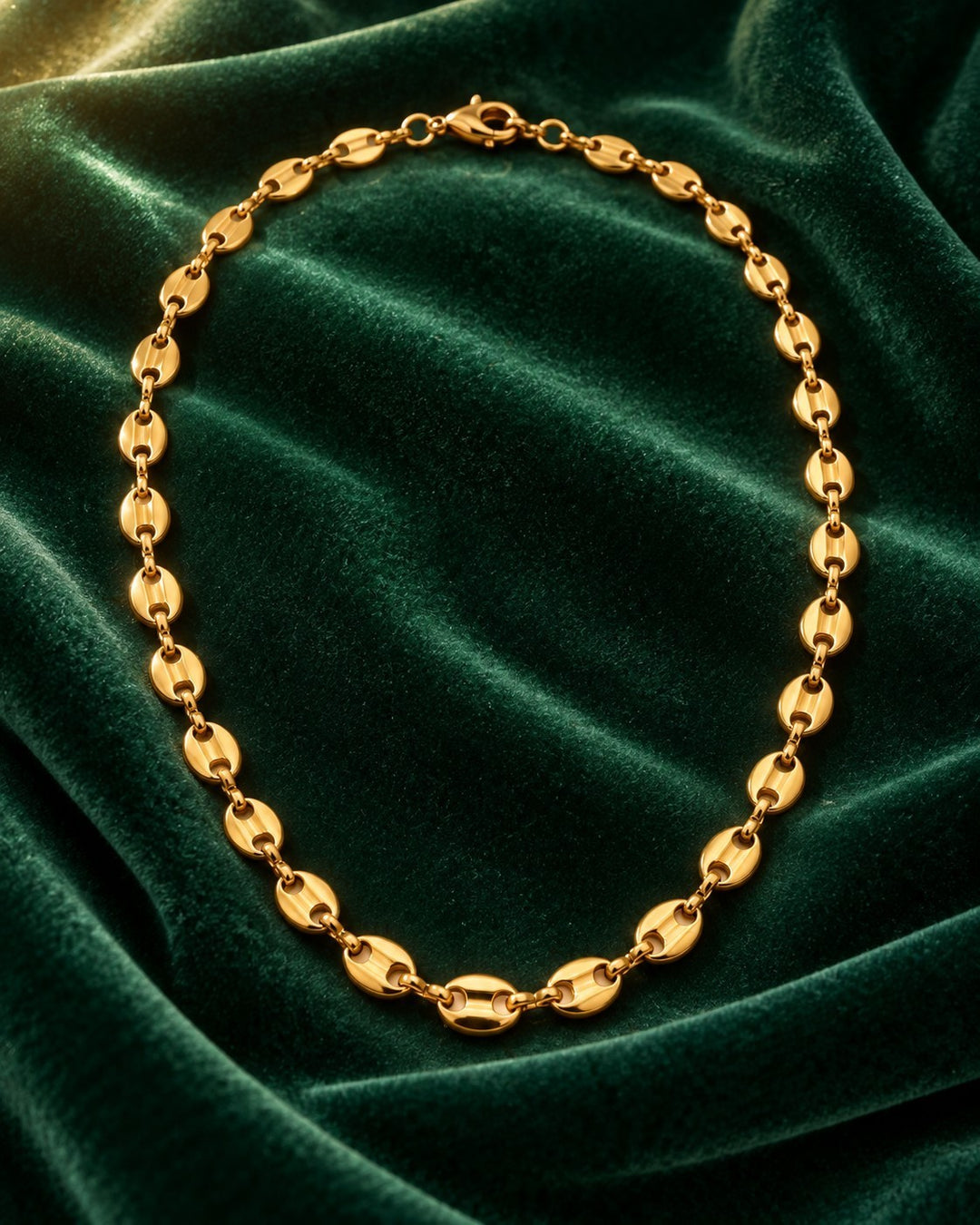 Elli Jewellery gold plated waterproof link chain choker necklace resting on a dark green velvet fabric background.
