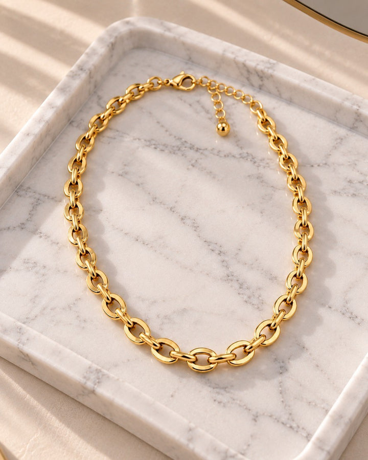 Elli Jewellery gold plated chunky link chain choker necklace resting on a white marble tray with soft sunlight