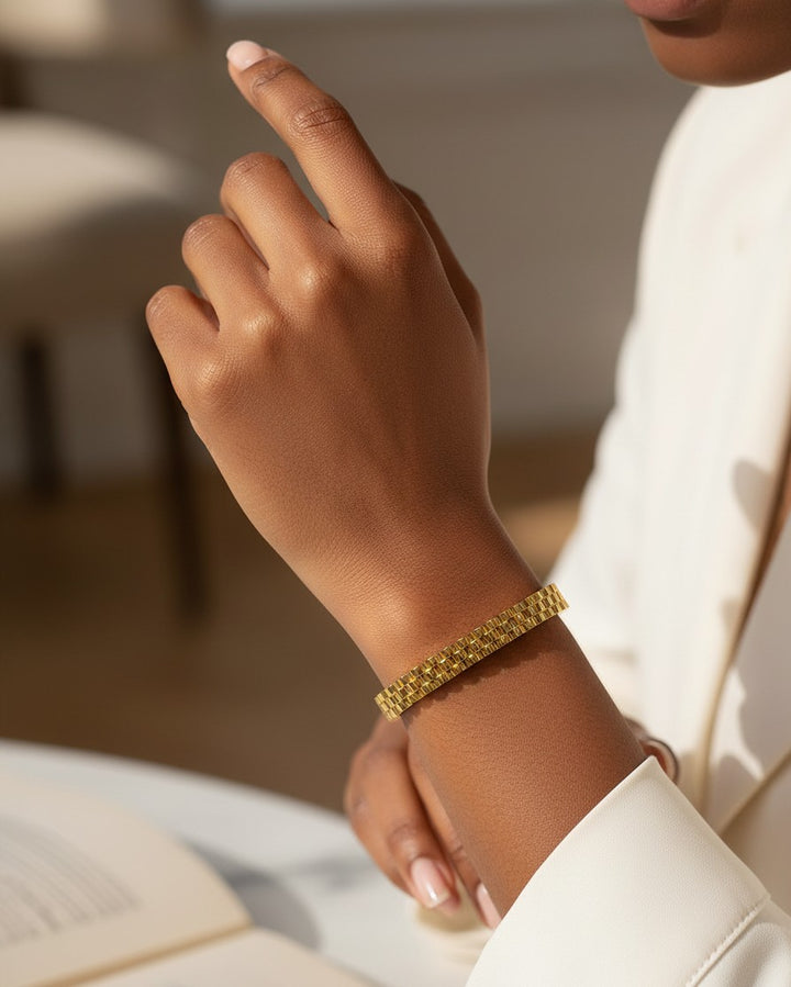 Elli Jewellery gold plated waterproof link style cuff bangle worn on a model's wrist with a white blazer