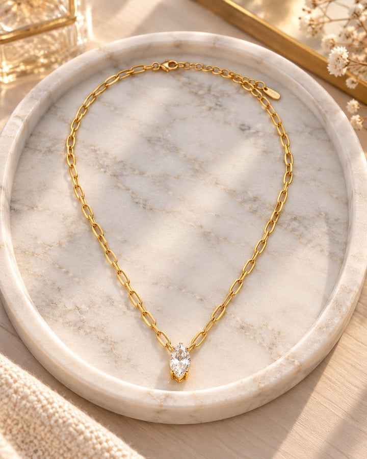 Elli Jewellery gold plated chain necklace with a marquise cut crystal pendant resting on a marble tray.