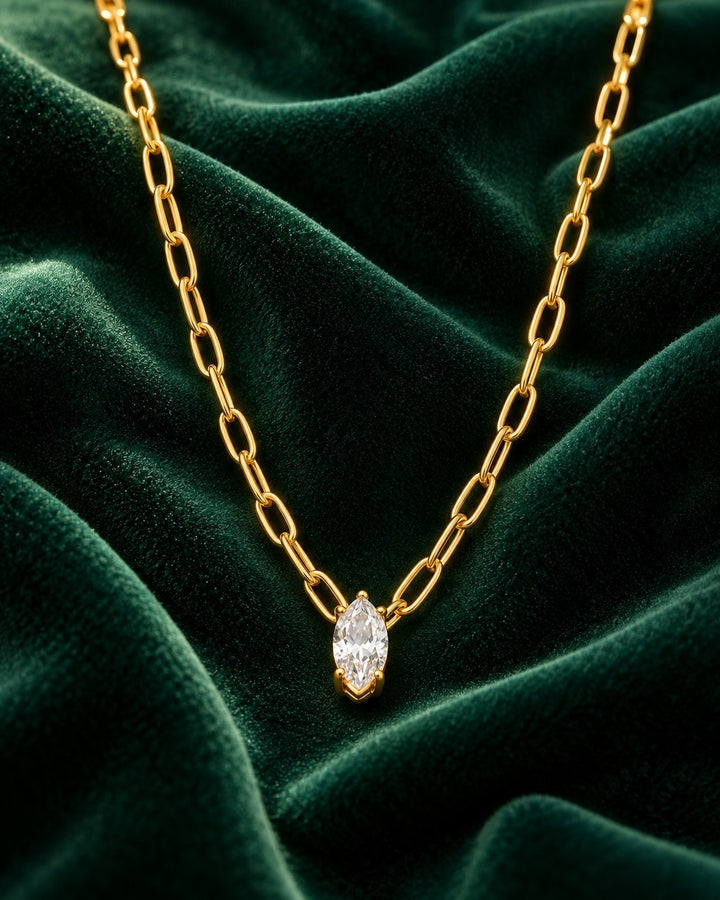 Elli Jewellery gold plated chain necklace featuring a marquise cut cubic zirconia pendant on a dark green velvet cloth