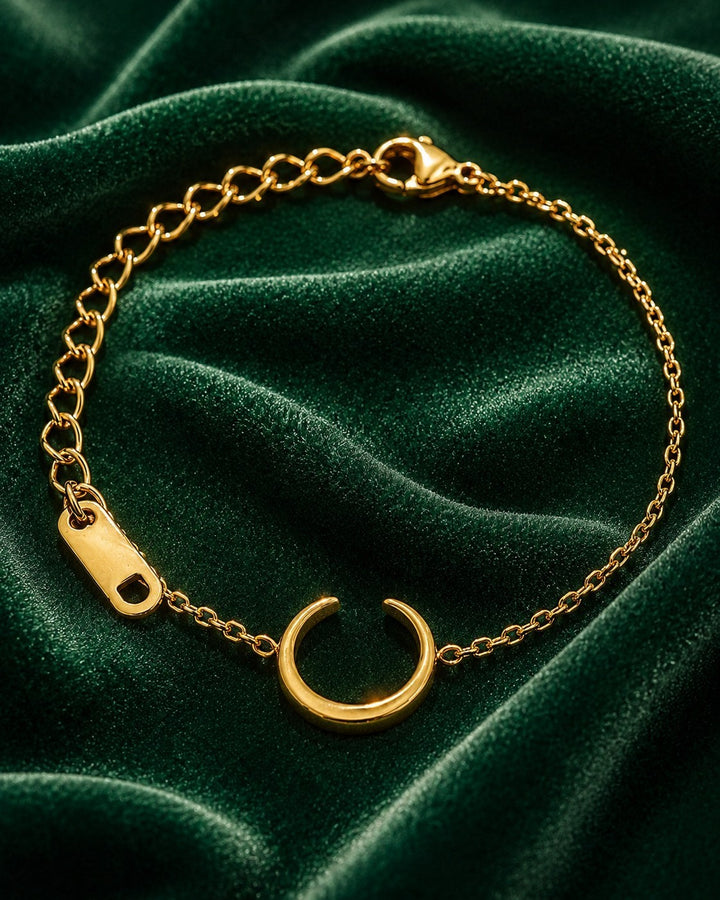 Elli Jewellery gold plated minimalist chain bracelet with a crescent charm on a dark green velvet background