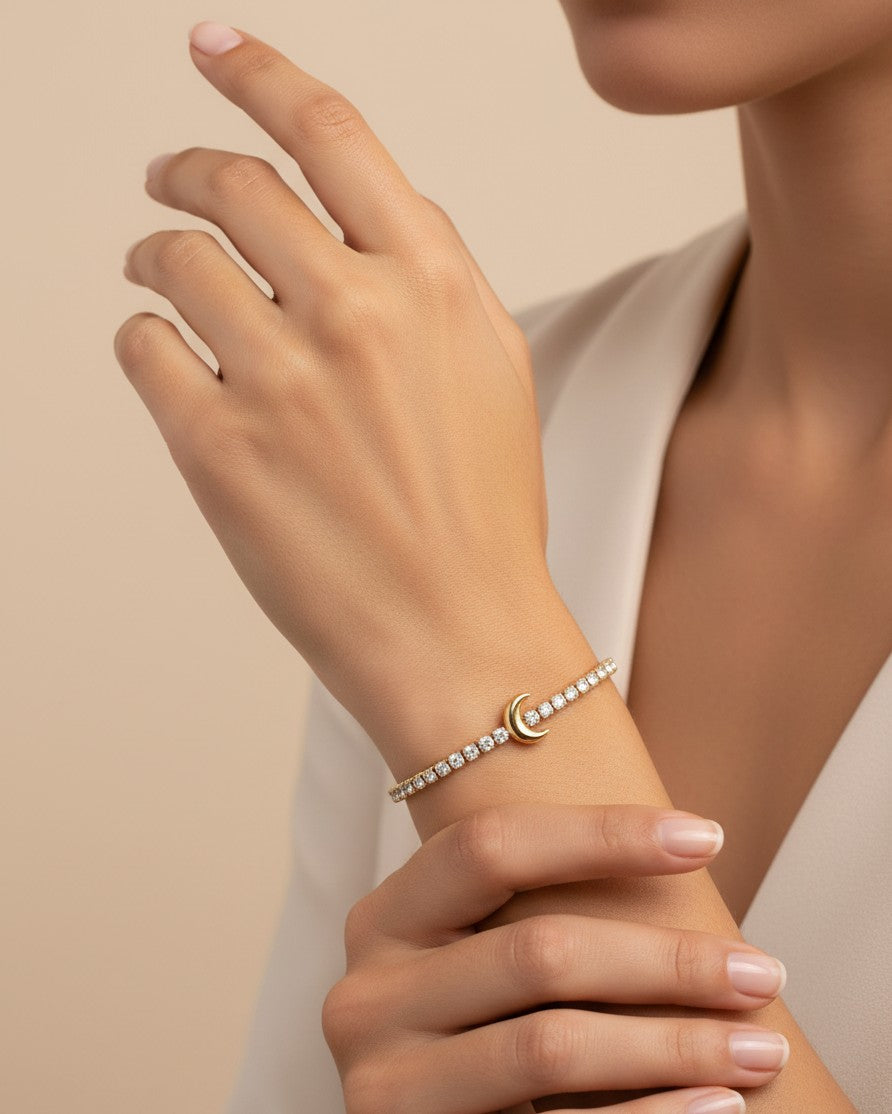 Elli Jewellery gold plated crescent moon charm bracelet with sparkling stones worn on a woman's wrist