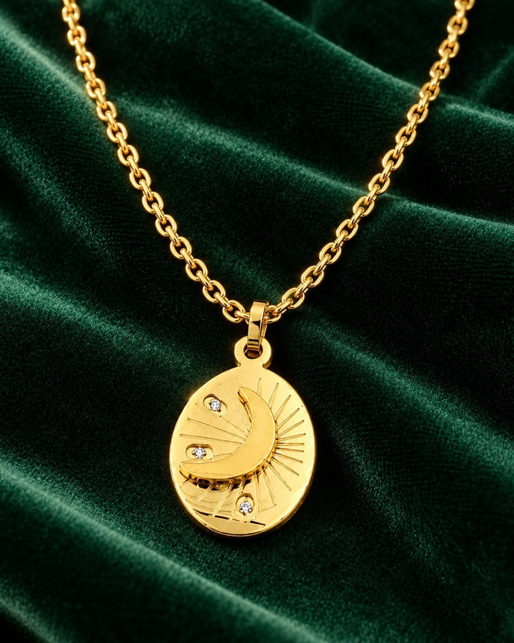Elli Jewellery gold plated oval pendant necklace featuring a crescent moon, star, and crystals on green velvet.