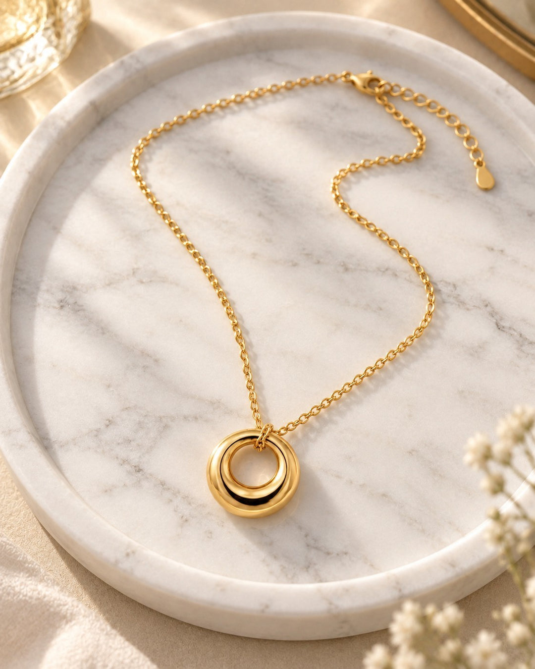 Elli Jewellery gold plated waterproof circle pendant necklace with ombré gradient effect on a marble tray