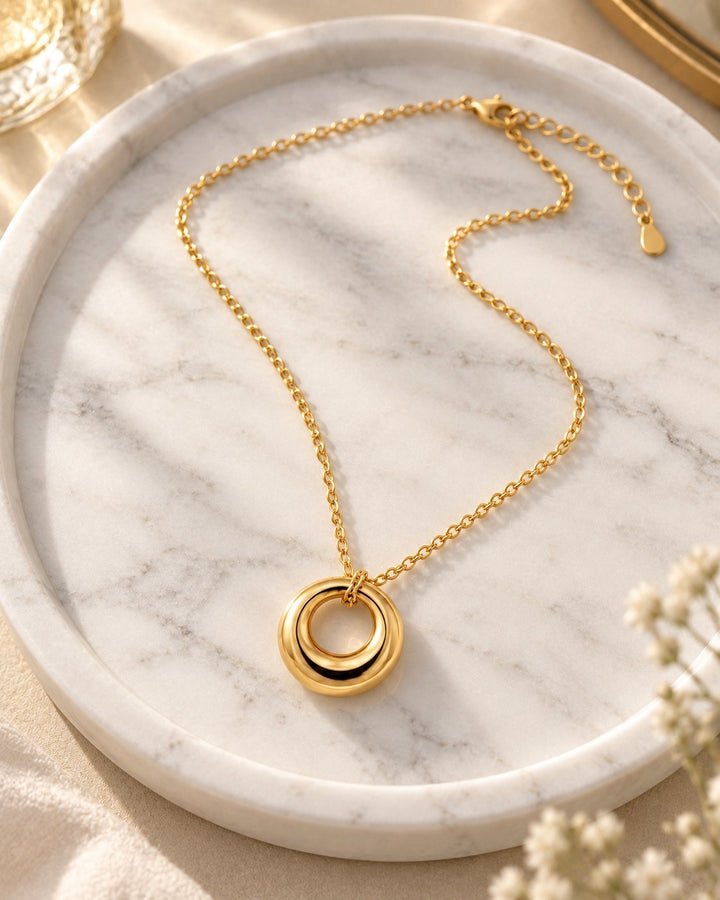 Elli Jewellery gold plated waterproof circle pendant necklace with ombré gradient effect on a marble tray