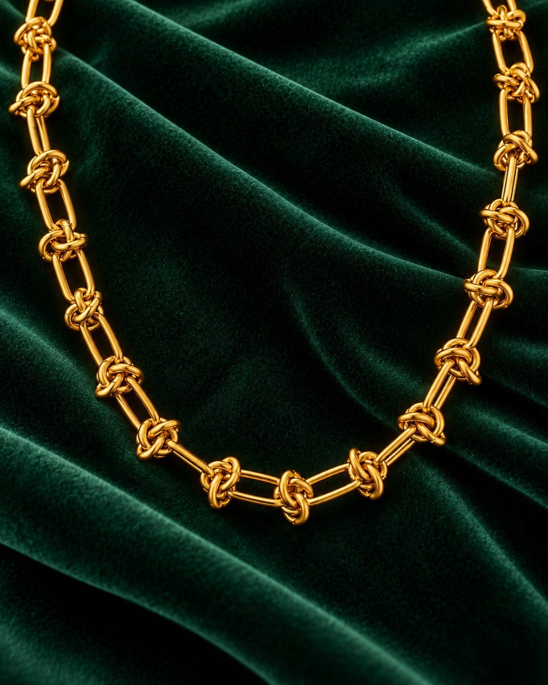 Elli Jewellery gold plated waterproof oval link chain necklace resting on a luxurious dark green velvet background.