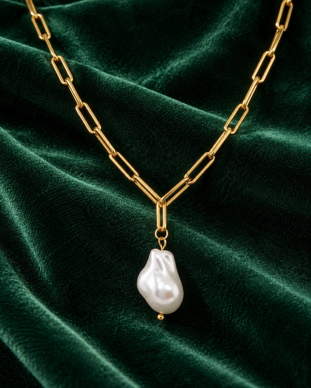 Elli Jewellery gold plated paperclip chain necklace featuring a lustrous baroque faux pearl pendant on green velvet.