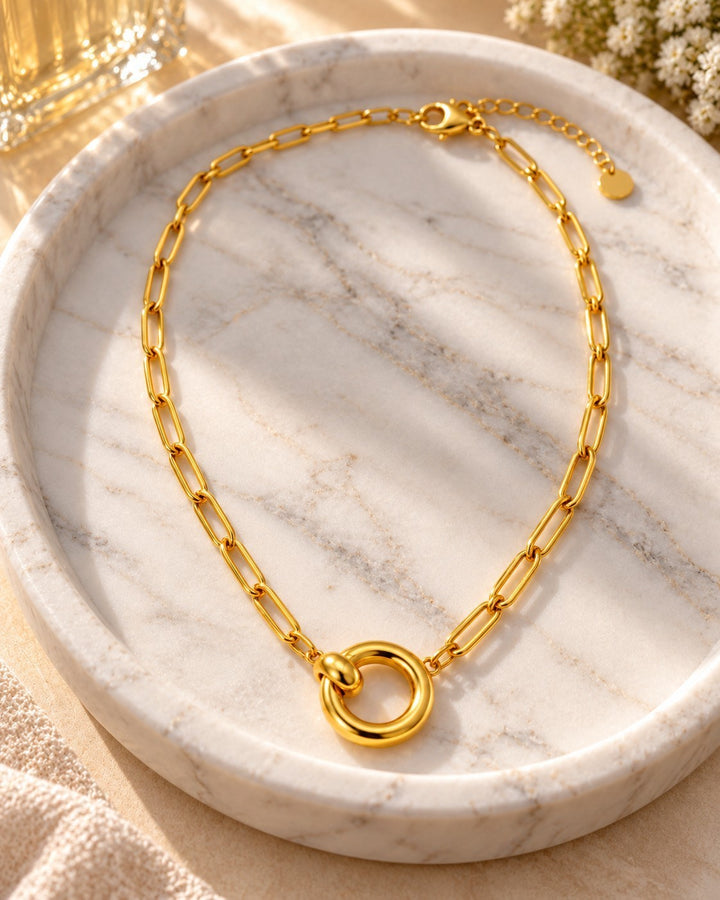 Elli Jewellery gold plated waterproof paperlink chain necklace with a minimalist round pendant on a marble tray.