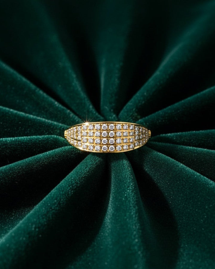 Elli Jewellery gold plated ring featuring a wide band with pavé crystals on a dark green velvet background.