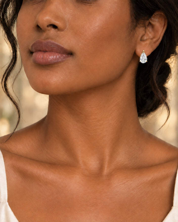 Model wearing Elli Jewellery gold plated pear shaped cubic zirconia stud earrings with a brilliant-cut teardrop stone.