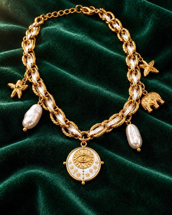 Elli Jewellery gold plated statement necklace with baroque pearls, elephant, and evil eye charms on green velvet.