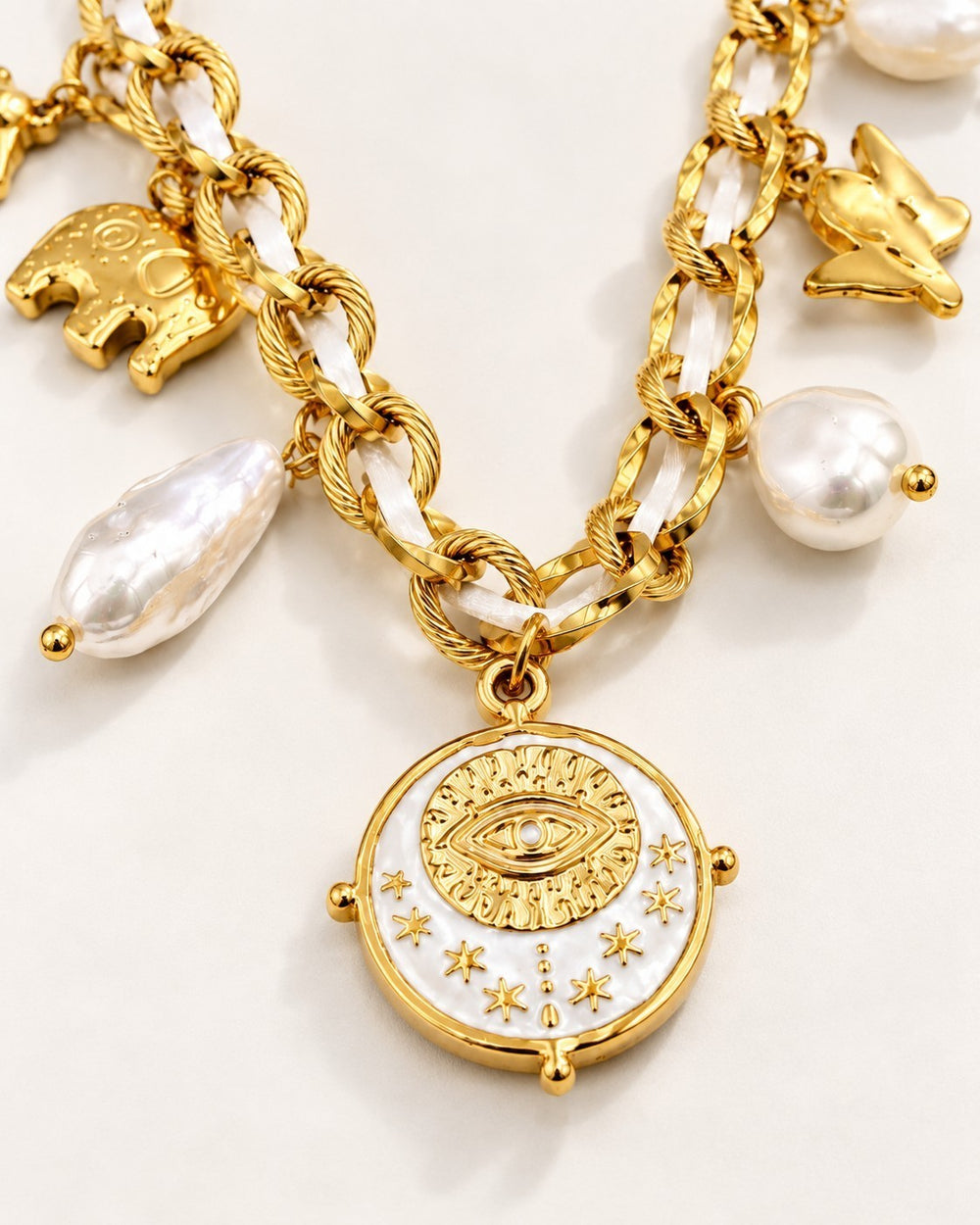 Elli Jewellery gold plated chain necklace featuring baroque pearl charms, an evil eye coin pendant, and elephant charm.