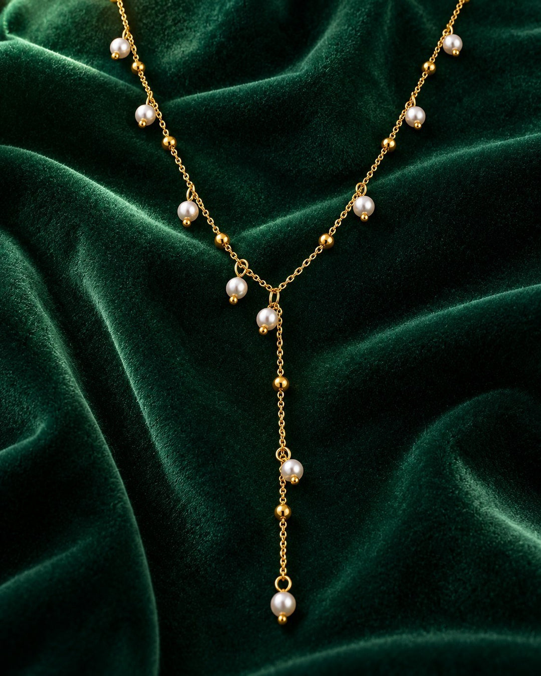 Elli Jewellery gold plated waterproof necklace featuring delicate chain with small pearls on a green velvet background