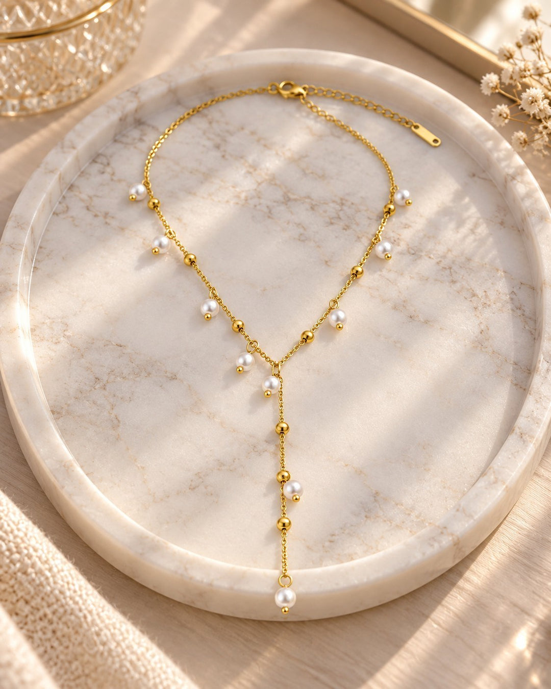 Elli Jewellery gold plated waterproof necklace featuring delicate chain with spaced pearl drops on a marble tray