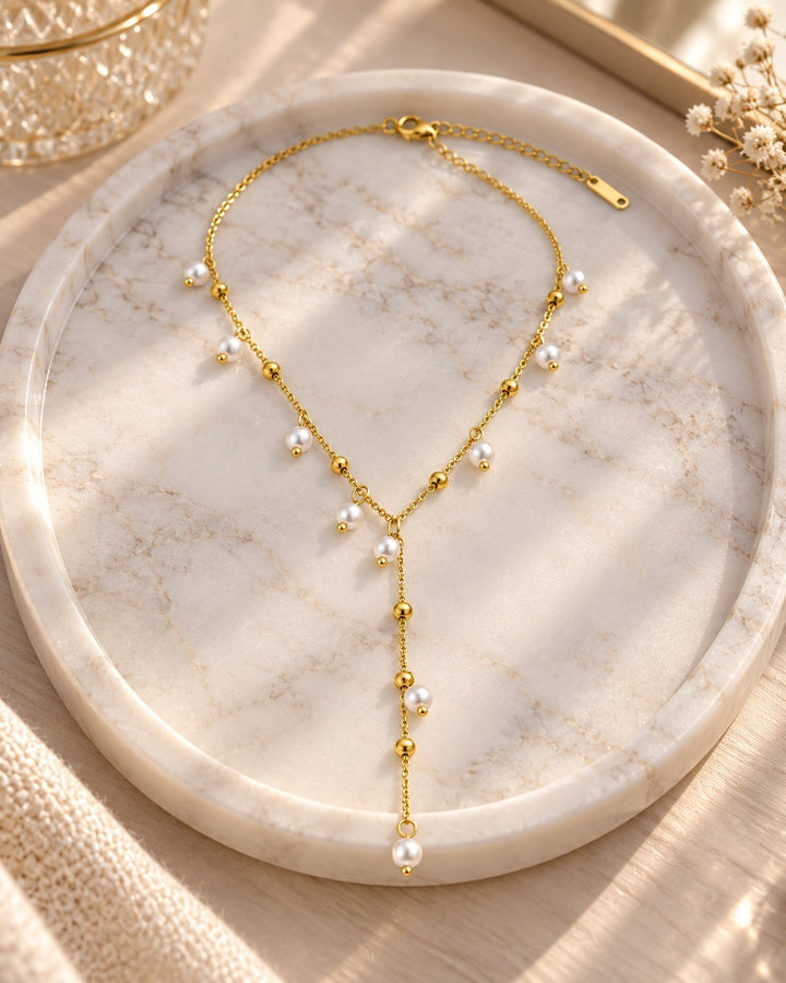 Elli Jewellery gold plated waterproof necklace featuring delicate chain with spaced pearl drops on a marble tray