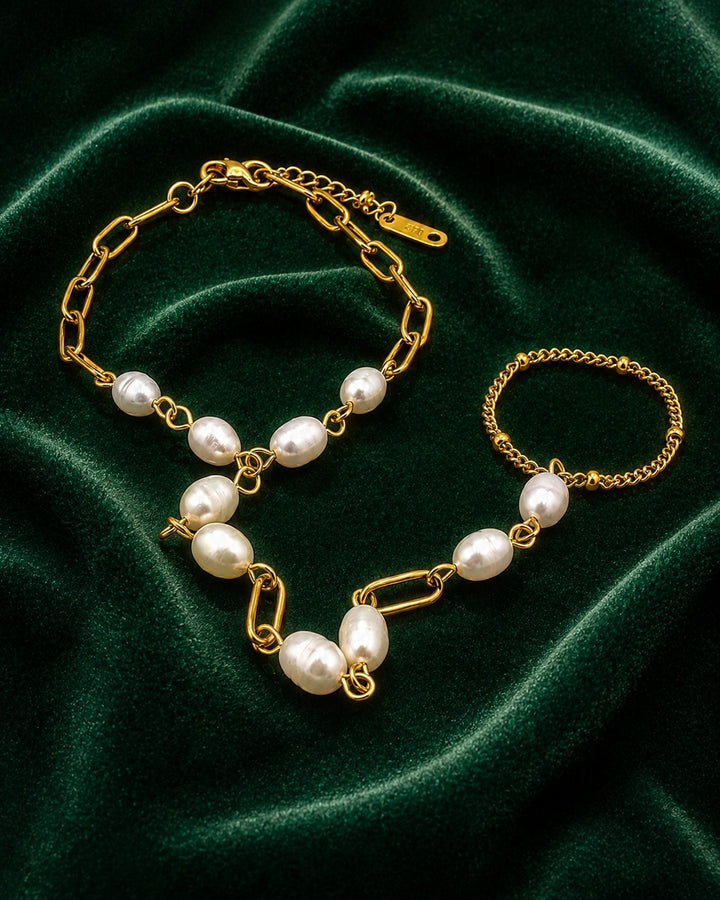Elli Jewellery gold plated hand chain bracelet featuring lustrous white pearls on a green velvet background