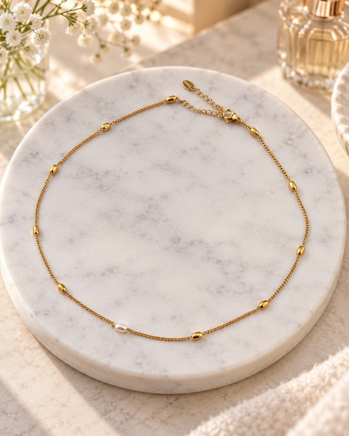 Elli Jewellery gold plated chain necklace with delicate freshwater pearl detail on a marble display stand.