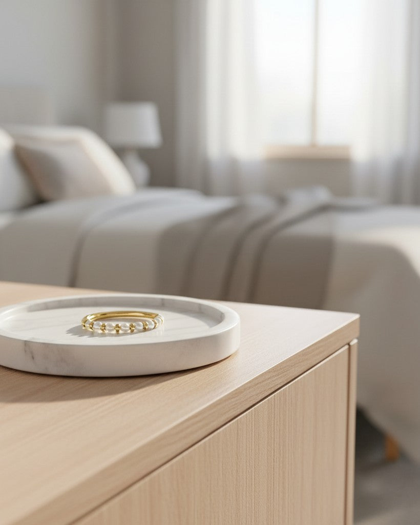 Elli Jewellery gold plated ring with freshwater pearl beads resting on a white marble tray in a bedroom setting.