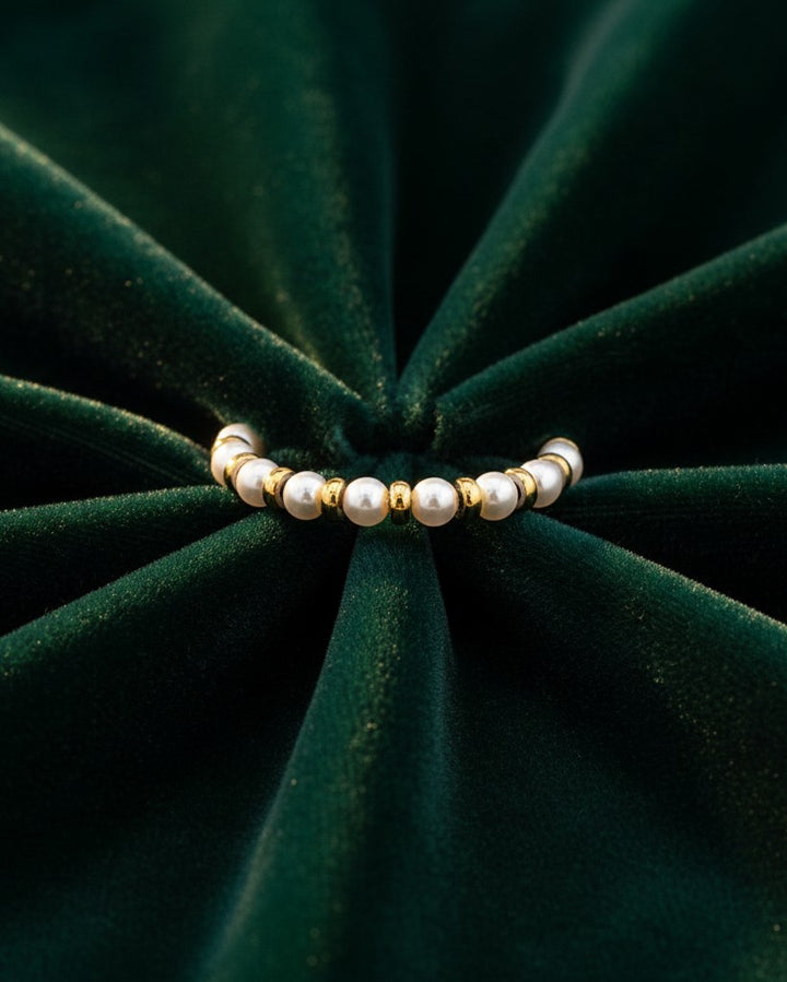 Elli Jewellery gold plated statement ring featuring alternating freshwater pearls on a dark green velvet background