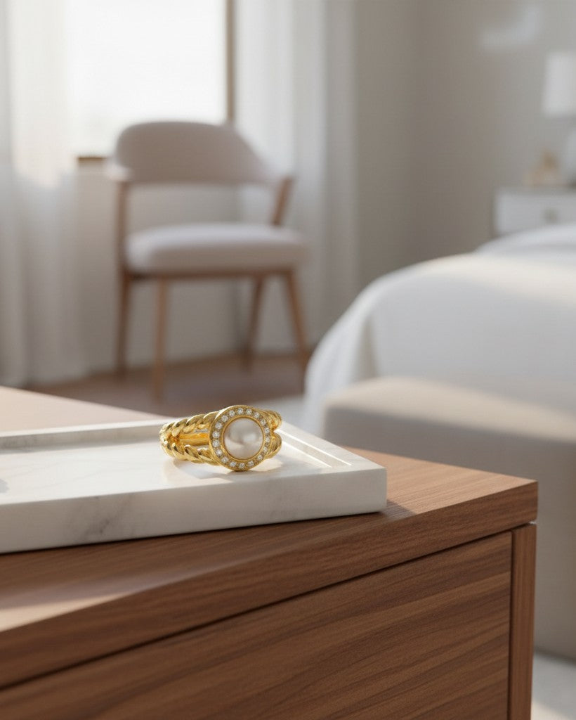 Elli Jewellery gold plated statement ring featuring a central pearl surrounded by sparkling zirconia pavé on a marble tray