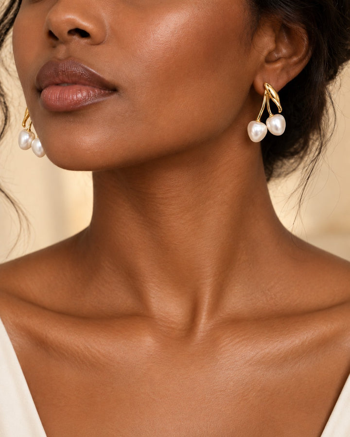 Elli Jewellery gold toned drop earrings featuring two lustrous pearl-effect beads on a model