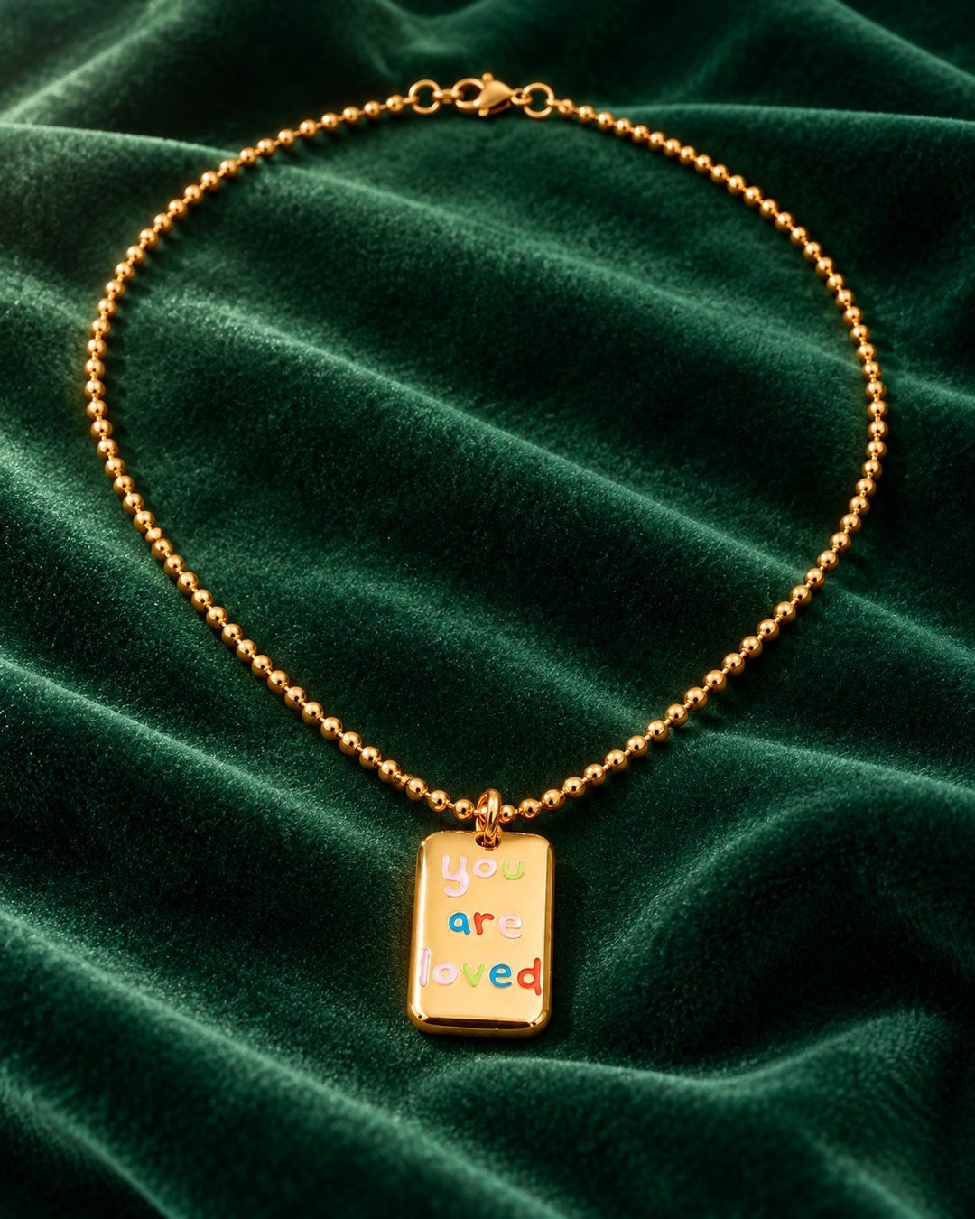 Elli Jewellery gold plated rectangular pendant necklace with colorful You Are Loved engraving on green velvet