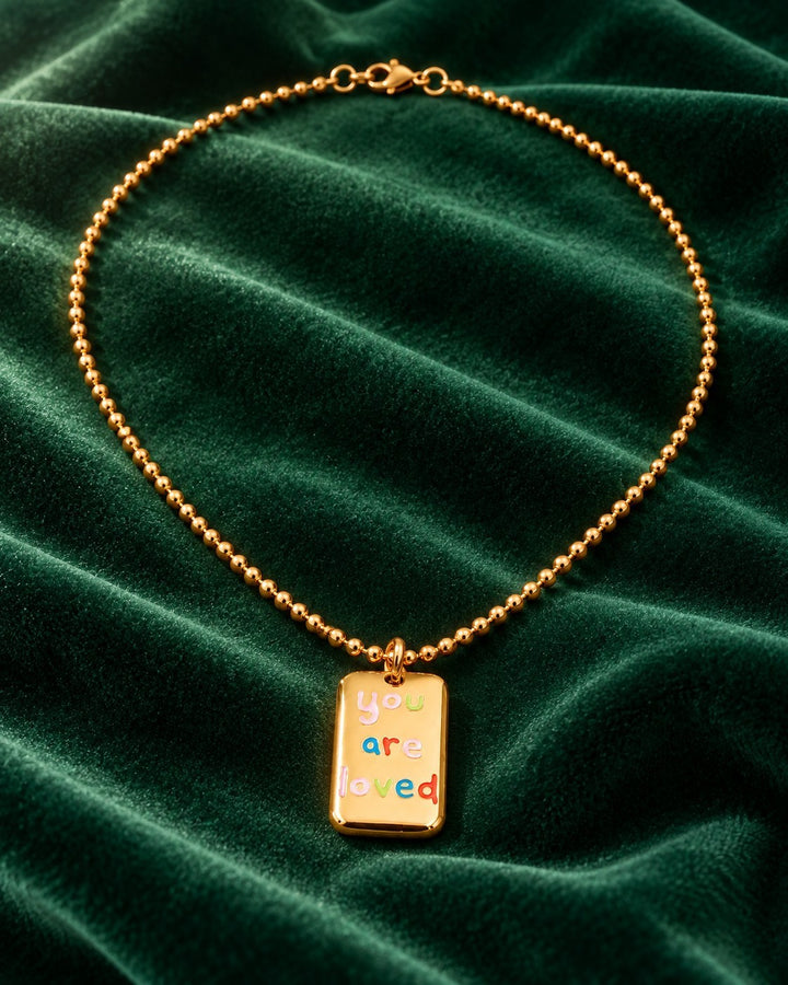 Elli Jewellery gold plated rectangular pendant necklace with colorful You Are Loved engraving on green velvet